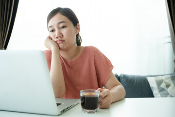 Young Asian woman bored in online meeting and work from home, woman tired in her work and online...