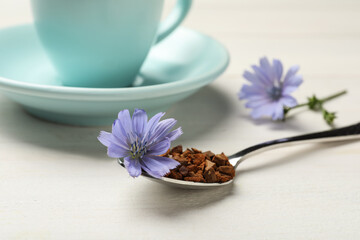 Obraz na płótnie Canvas Spoon of chicory granules with flower on white wooden table, closeup