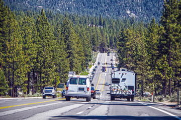 Busy traffic, including RVs on road surrounding South Lake Tahoe with forest and mountains