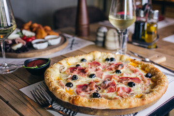 Pizza with prosciutto and olives with wine in restaurant