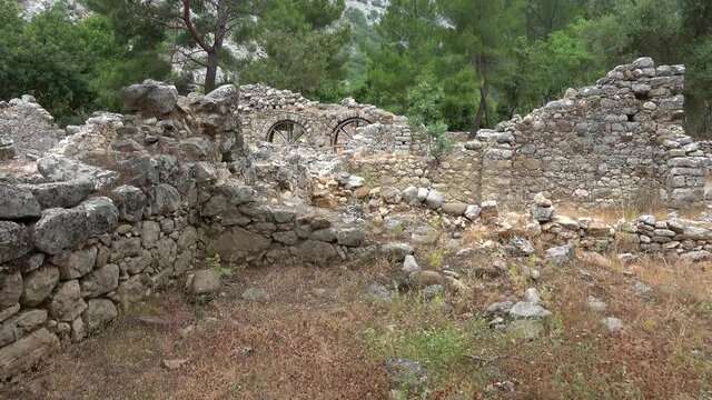 Olimpos, Antalya, Turkey - 29th of May 2021: 4K Viewing ruined houses of Olimpos city between pine trees
