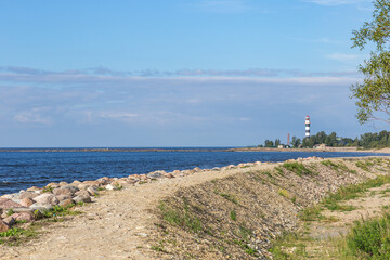 Fototapeta na wymiar sandy road along the sea and in the distance a lighthouse 