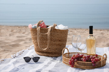 Bag, blanket, wine and other stuff for beach picnic on sandy seashore