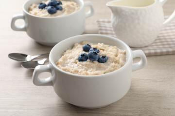 Tasty oatmeal porridge with blueberries in bowl served on wooden table