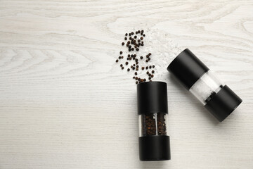 Salt and pepper shakers on white wooden table, flat lay. Space for text