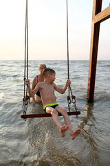 Woman rocks kid on swing in Sea of Azov