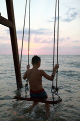 Boy sitting on swing in Sea of Azov