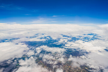 Aerial view scene of the mountain, meadow and abundant rice which hiding under white fluffy clouds and blue bright sky background.