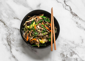 Buckwheat noodles with chicken, vegetables and mushrooms - delicious asian style lunch on a light background, top view