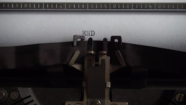 Typing word End on retro typewriter. Close up.
