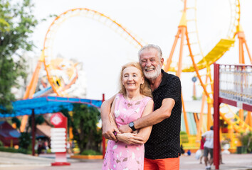 Happy senior couple embracing in the theme park. Smiling elderly couple hugging in amusement Theme park. family, age, tourism, travel and people concept