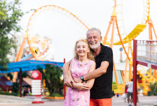 Happy senior couple embracing in the theme park. Smiling elderly couple hugging in amusement Theme park. family, age, tourism, travel and people concept