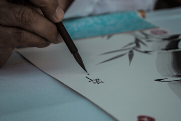 mano de un japonés escribiendo letras chinas con tinta
