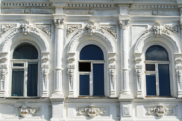 The facade of an old building with plaster ornaments and arched windows. Flat lay of the frame. Close-up