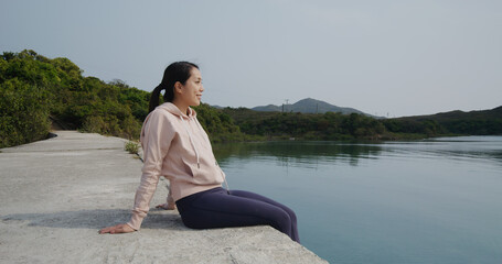 Fototapeta premium Woman sit at the pier and enjoy the sea view