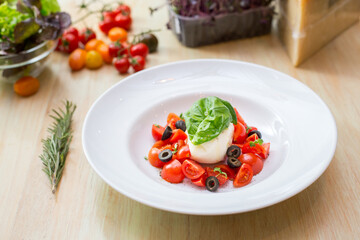 Plate with fresh salad with tomatoes, basil leaves and mozzarella 