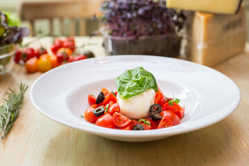 Plate with fresh salad with tomatoes, basil leaves and mozzarella 