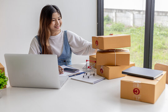 An online seller is counting the number of parcel boxes in preparation for shipping to customers, brown parcel boxes tied with ropes to avoid damage. Online shopping concept.