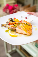 Salomon with vegetables on plate in restaurant