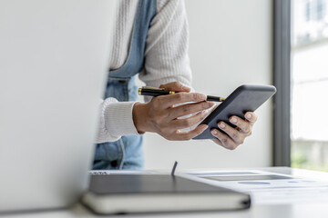 businesswoman holding a mobile phone, she is looking at information on mobile phone that the financial officer sends through an online messaging program. Financial concepts.