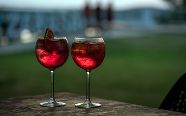 Two glasses with a carbonated drink and ice cubes on the background of the evening sky