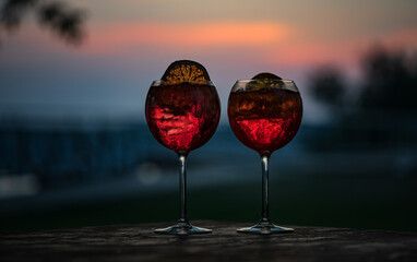 Two glasses with a carbonated drink and ice cubes on the background of the evening sky