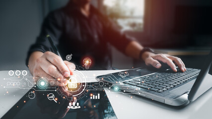 The businessman working on his laptop at home selects the icon security on the virtual screen. The...