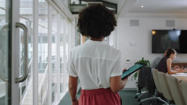 rear view mixed race business woman walking through office holding tablet computer successful career in corporate workplace 4k