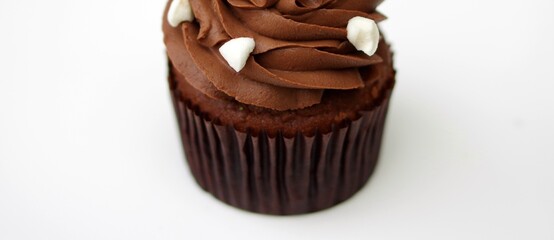 Dark chocolate cupcake with brown paper liner white background with copy space banner