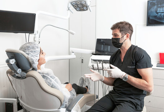 Dentista habla con su paciente mujer, explicandole que trabajo realizará en su boca