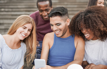Obraz premium Multiracial young friends using mobile phone in the city - Diverse people having fun outdoor