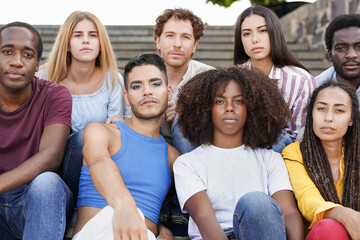 Group of diverse friends sitting in the city and looking serious on camera - Multiracial people and diversity concept - obrazy, fototapety, plakaty