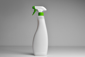 White plastic spray bottle on isolated background. mpty place for text or logo on gray background....