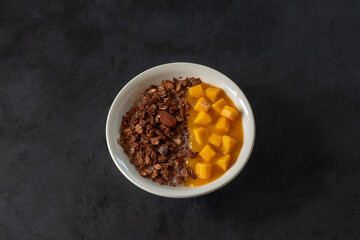 Fototapeta premium Healthy breakfast without milk: granola with Belgian chocolate with oat milk and mango pieces and mango puree in a jar.