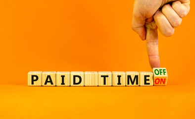 Paid time off or on symbol. Businessman turns a wooden cube and changes words 'paid time on' to 'paid time off'. Beautiful orange background. Business and paid time off or on concept, copy space.