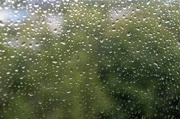 raindrops on window glass, selective focus, rainy city background, wet glass, texture of raindrops