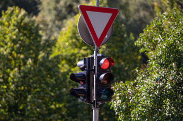 road sign GIVE WAY and traffic semaphore with red light against the defocused background, close-up