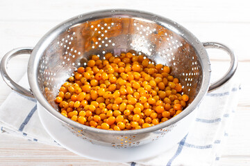 Fresh sea buckthorn in a colander. Harvesting sea buckthorn for the winter. Frozen sea buckthorn