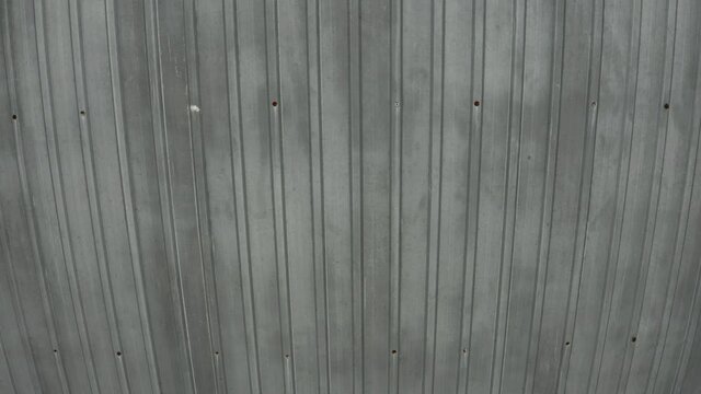 Moving along the tin plates of a relatively new tin roof, showing the nails, dents and leaks during a roof inspection