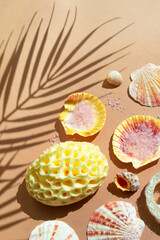 Natural spa and skincare beauty cleansing products: sponge, salt, sea shells. Flat lay pattern on beige background palm leaf shadow.