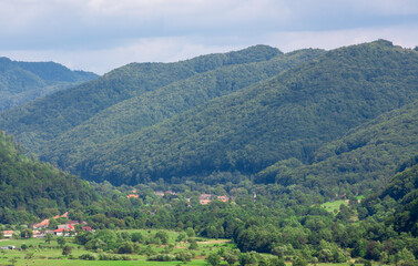 Naklejka na ściany i meble landscape with a village between the mountains of Transylvania