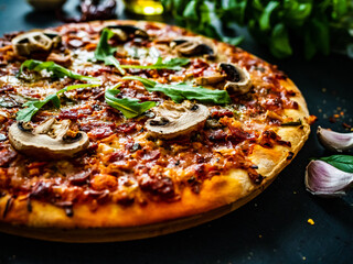 Circle pizza with mozzarella, white mushrooms, salami and tomatoes on wooden table

