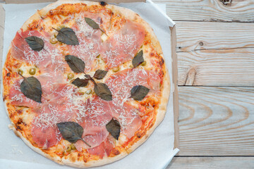 Pizza with prosciutto parma ham meat close up. Appetizing meat pizza with cheese and basil leaves...