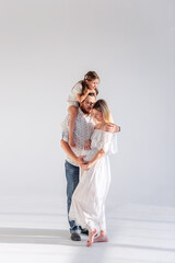 Fototapeta na wymiar Young modern family have fun together in white loft interior. Mother pregnant, father holds daughter