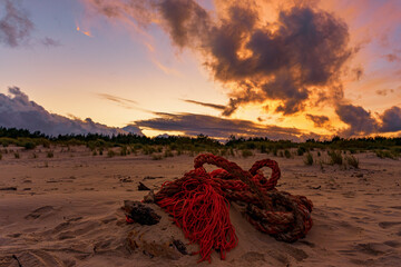 Czerwony zachód słońca, czerwona lina na piasku.
