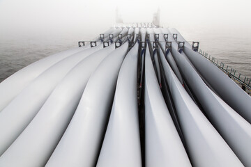Transportation of blades for wind turbines on a cargo ship across the ocean in fog.