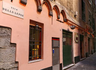 Characteristic alley and old building facade with road name sign in the historic center of Genoa.