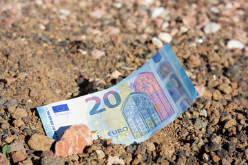 Twenty euro bill on soil ground with stone on top. Land investment, property money investor, bargain project, bet on life concepts