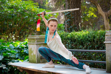 
Young woman practicing tai chi with a sword in an outdoor park