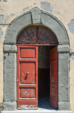 Fototapeta Detail of the open door of an old palace, with a stone arched frame and cracked paint, Livorno, Tuscany, Italy